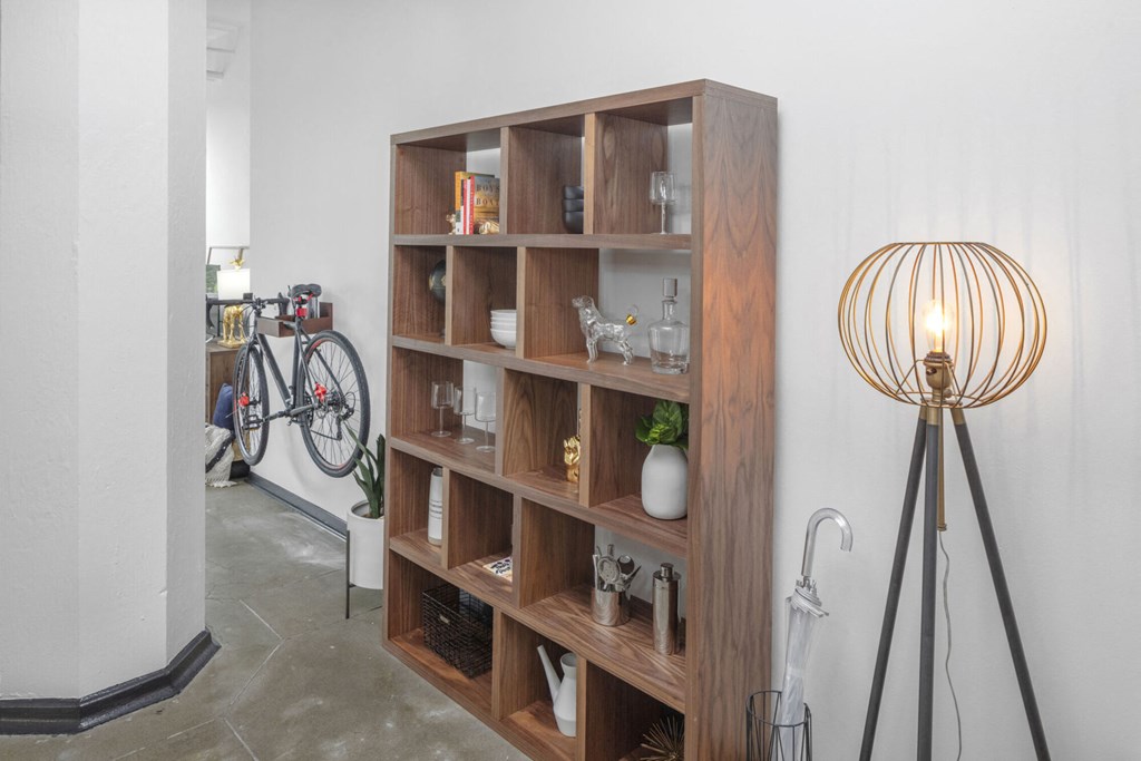 a bookshelf in the corner of a room with a bike and a lamp
