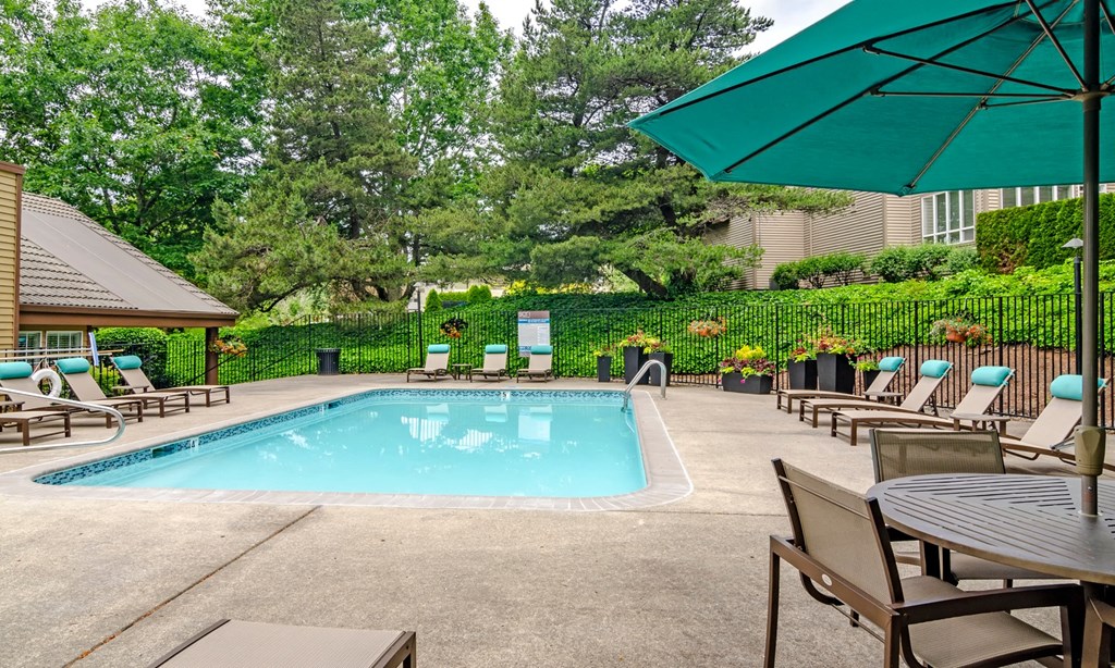 our resort style swimming pool is surrounded by chairs and umbrellas