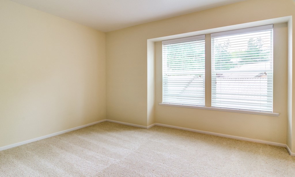 an empty room with a large window with blinds