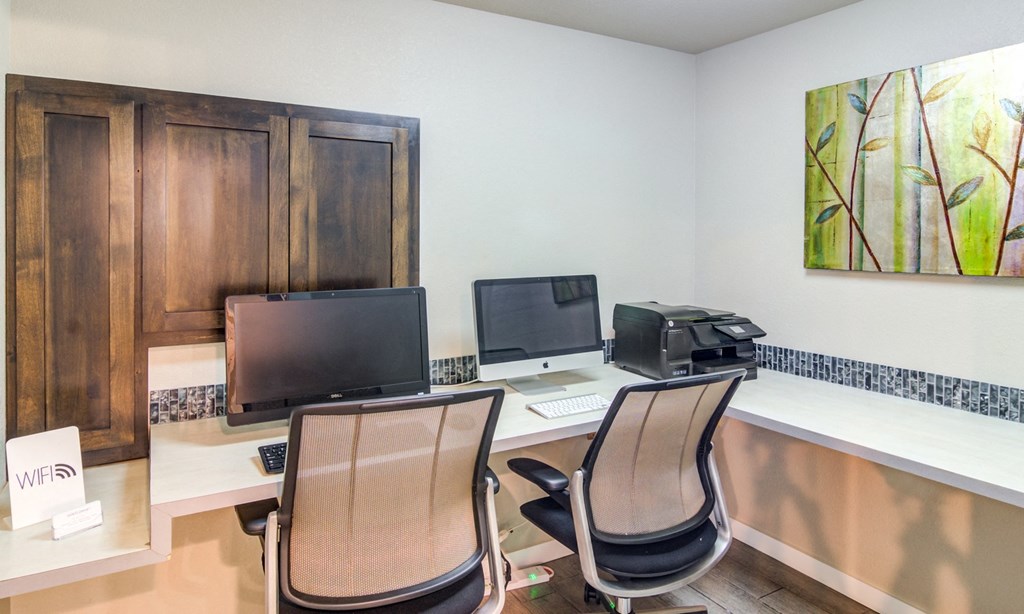 an office with two computers and a printer on a desk