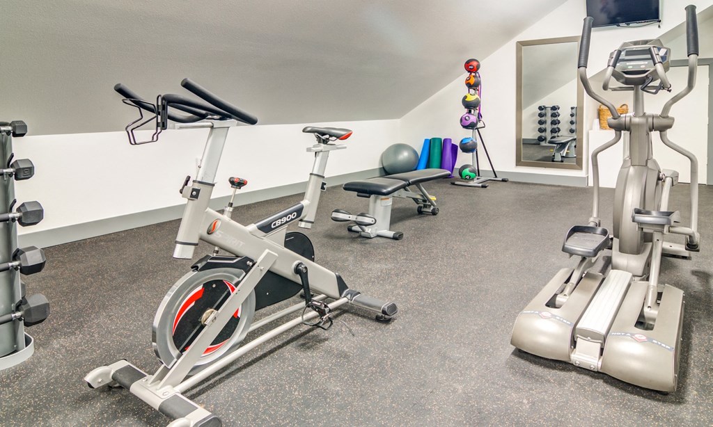 a gym with exercise bikes and weights in a room with a mirror