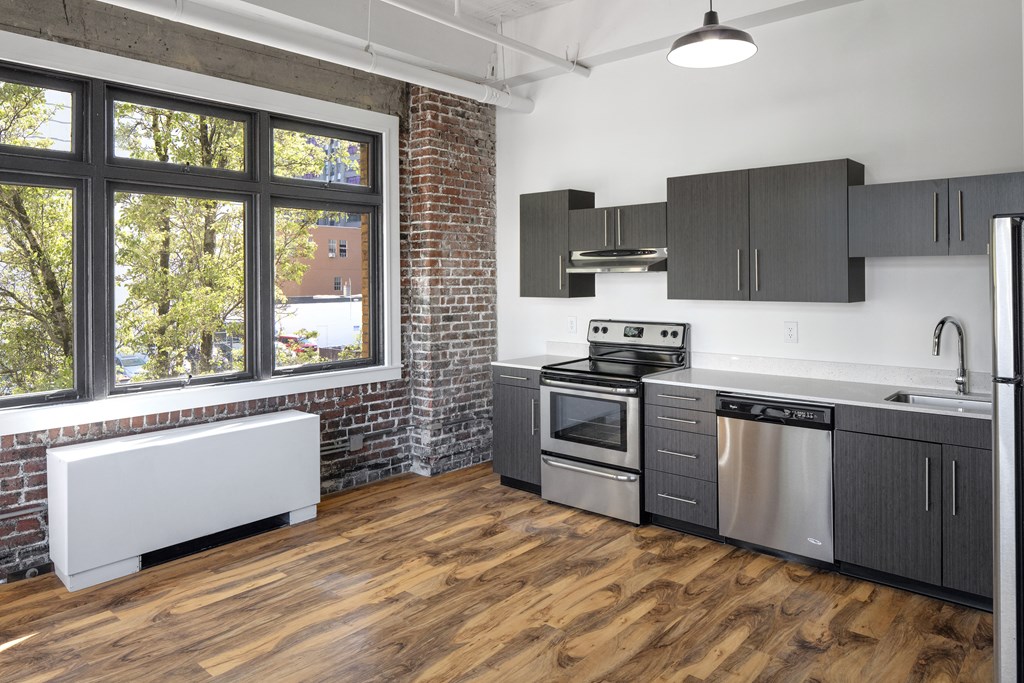a kitchen with a large window and stainless steel appliances and wooden floors