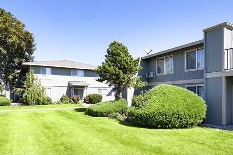 the exterior of an apartment building with a lawn and bushes