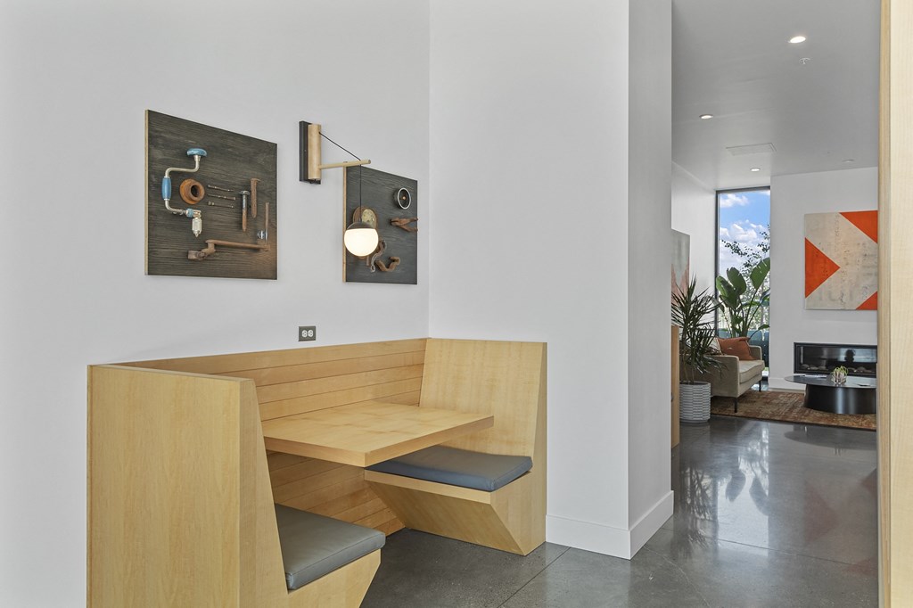 a seating area with a wooden desk and two paintings on the wall
