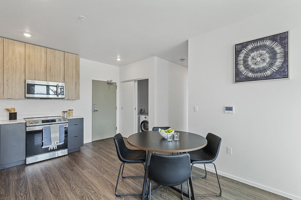 a dining area with a table and chairs and a kitchenette with a stove microwave and sink