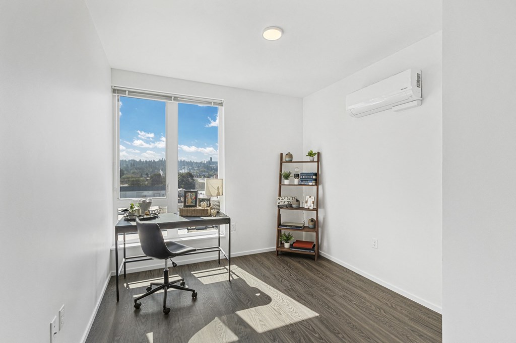a home office with a desk and a large window