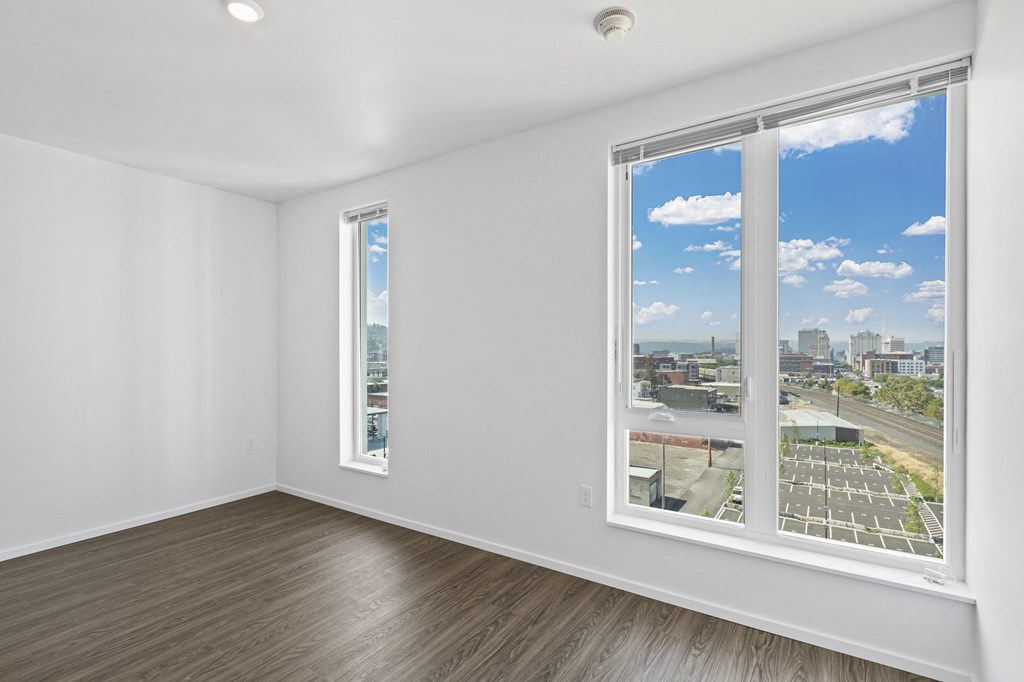an empty room with three windows and a view of the city