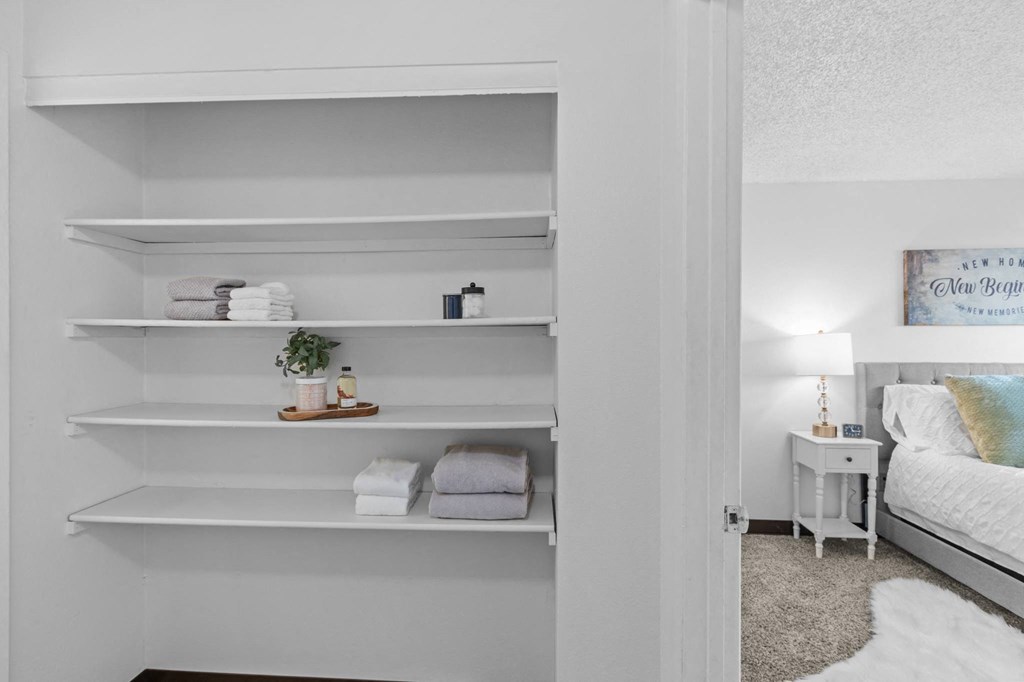 a bedroom with white shelves and a bed and a white closet