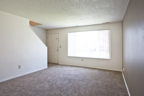 an empty living room with a large window and carpet