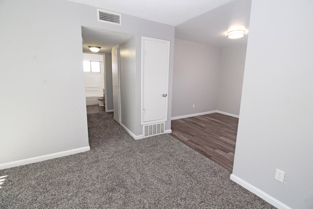 an open living room and bedroom with hardwood flooring and white walls