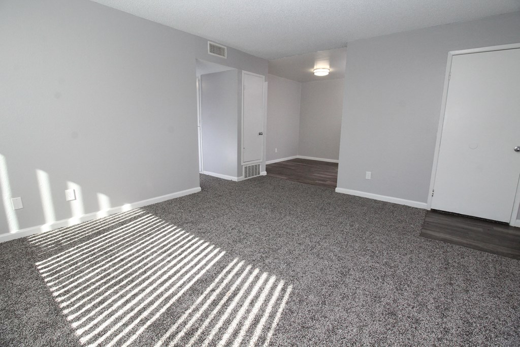 an empty living room with carpet and white walls