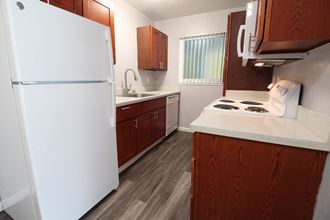 a kitchen with white appliances and wood cabinets and a white refrigerator