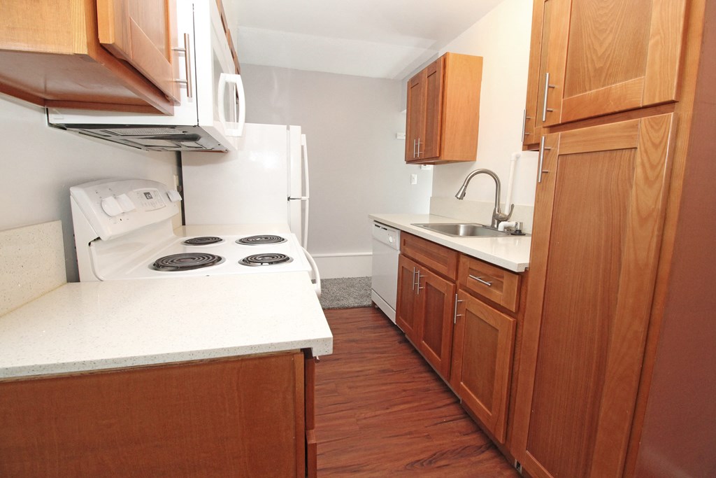 an empty kitchen with wooden cabinets and a white counter top