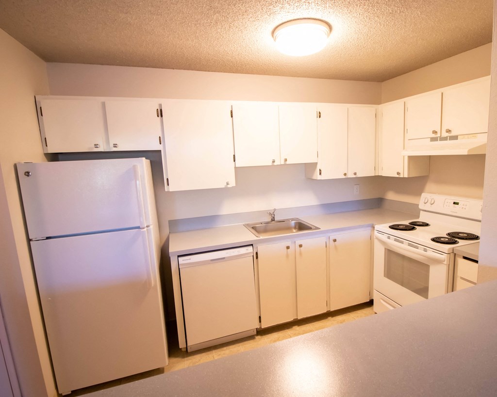 an empty kitchen with white appliances and white cabinets