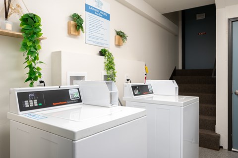 Two washing machines are on display in a room with a sign on the wall.