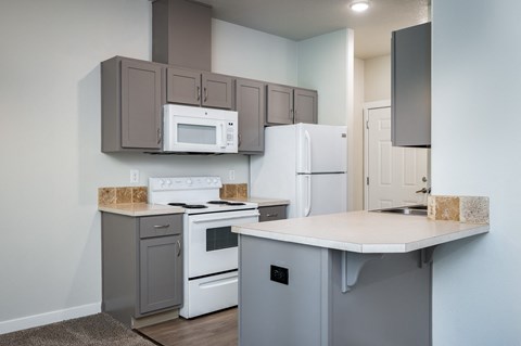 a kitchen with white appliances and gray cabinets and a counter top