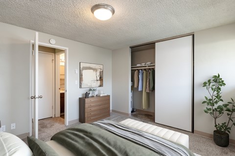 A bedroom with a bed, a wardrobe, and a plant.