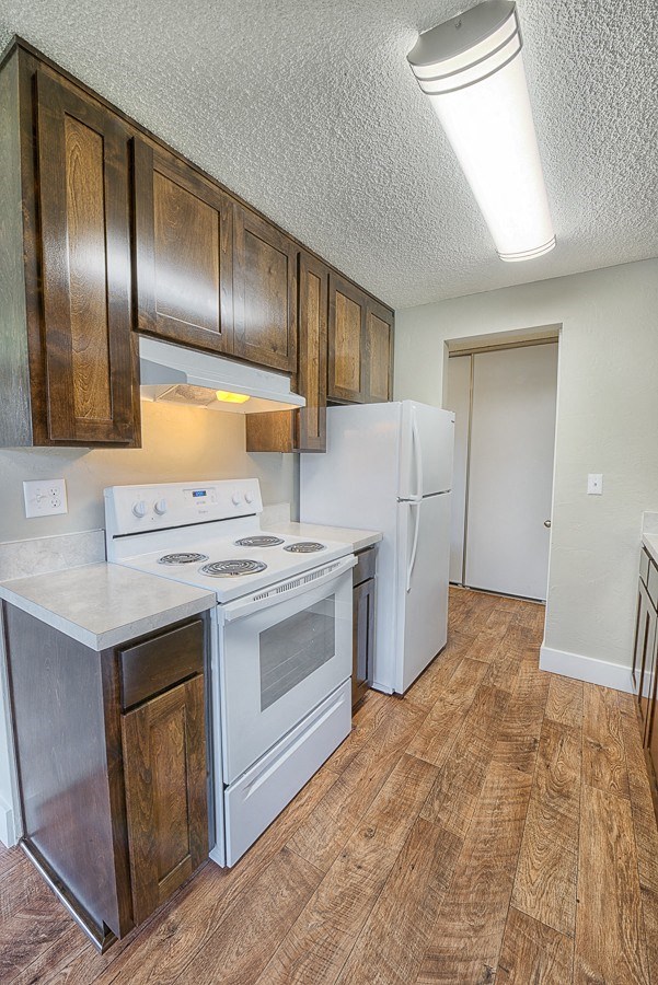 A kitchen with a white stove and wooden cabinets.