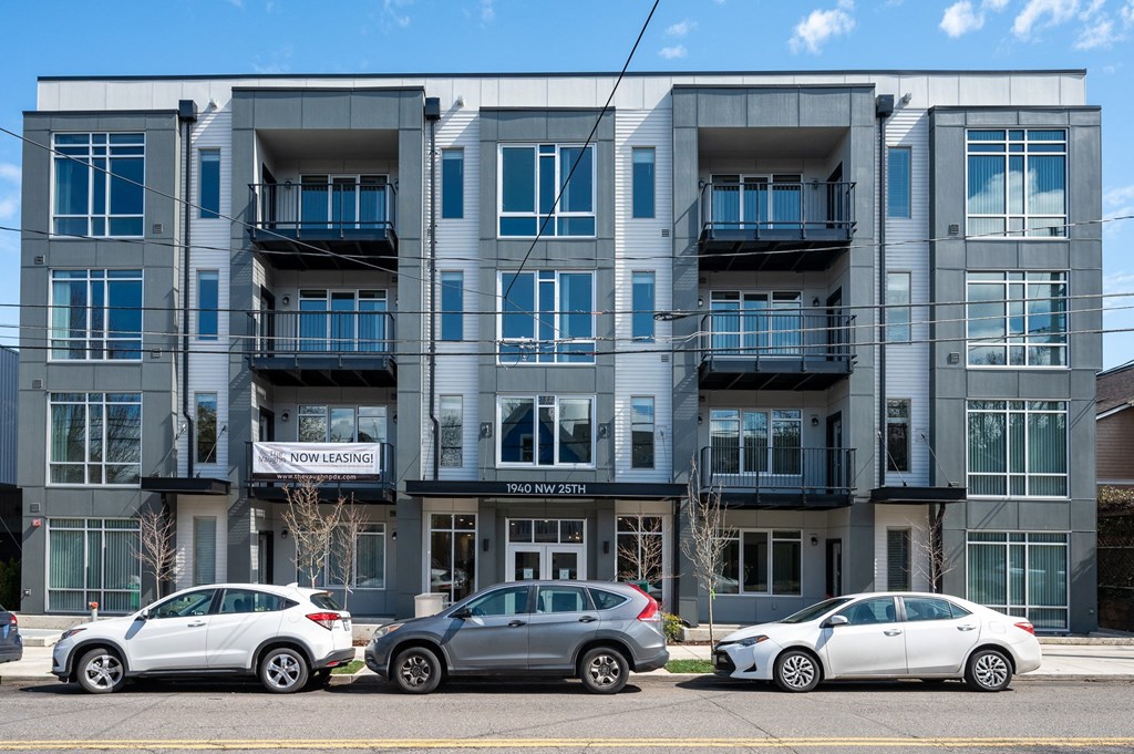 an image of an apartment building with cars parked in front of it