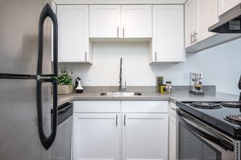 a kitchen with white cabinets and a sink and a refrigerator