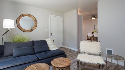 A living room with a blue couch and a round mirror on the wall.