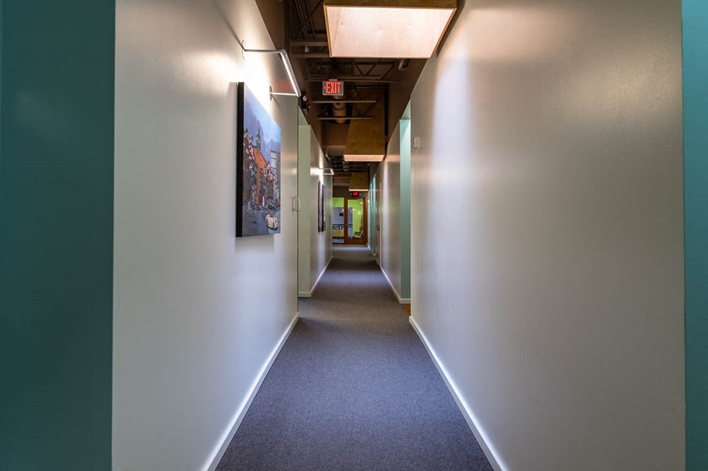 a hallway in a building with white walls and a blue carpet