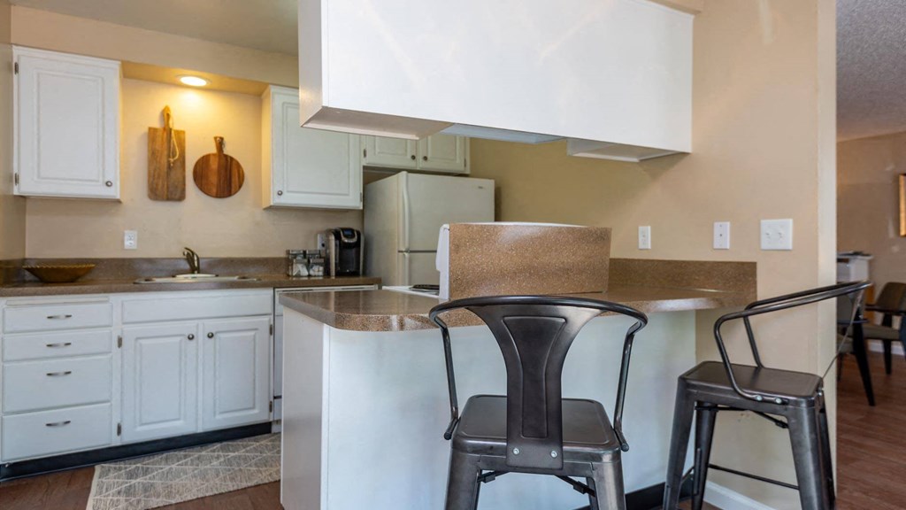 a kitchen with white cabinets and a counter with two stools