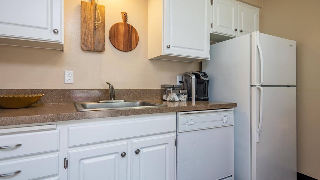 a kitchen with white cabinets and a sink and a refrigerator