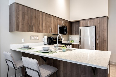 a kitchen with a island with two chairs and a stainless steel refrigerator