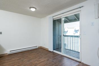 an empty living room with a sliding glass door to a balcony