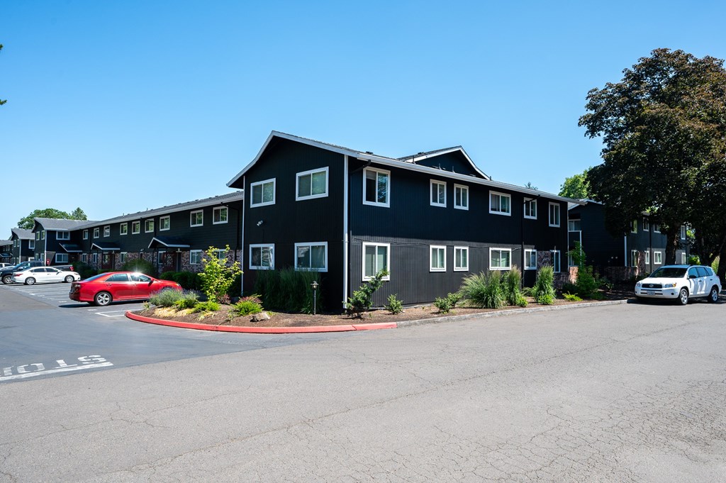 A black building with a parking lot in front of it.