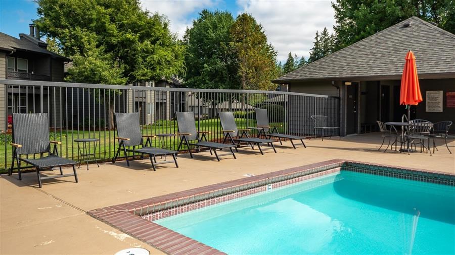 a swimming pool with chairs next to a building