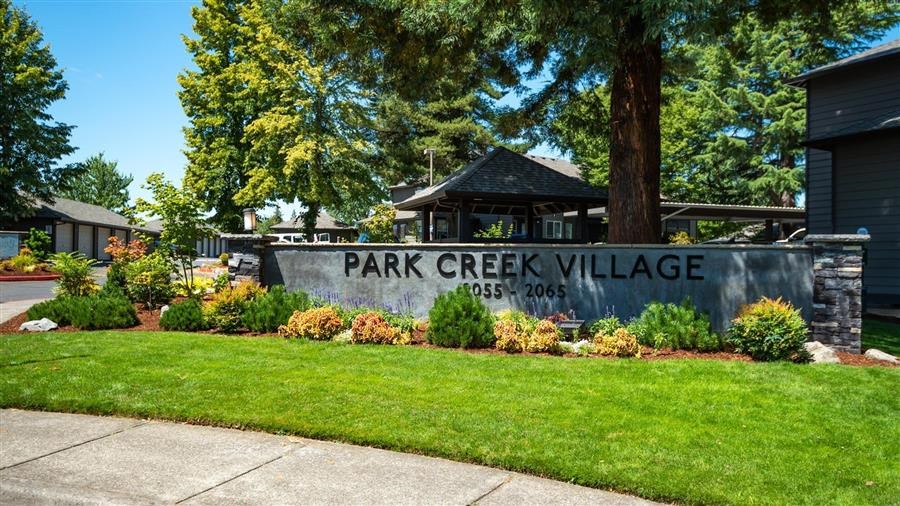 a park creek village sign in front of a tree