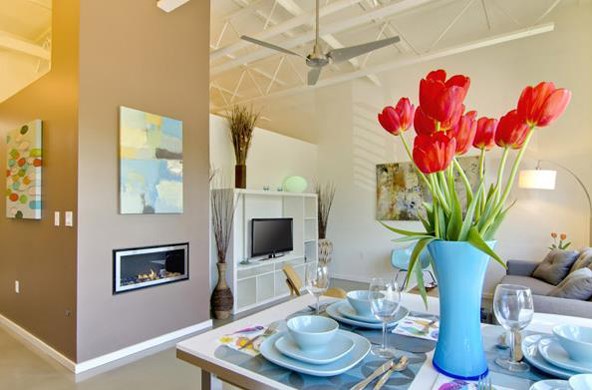 a living room with a table with red flowers