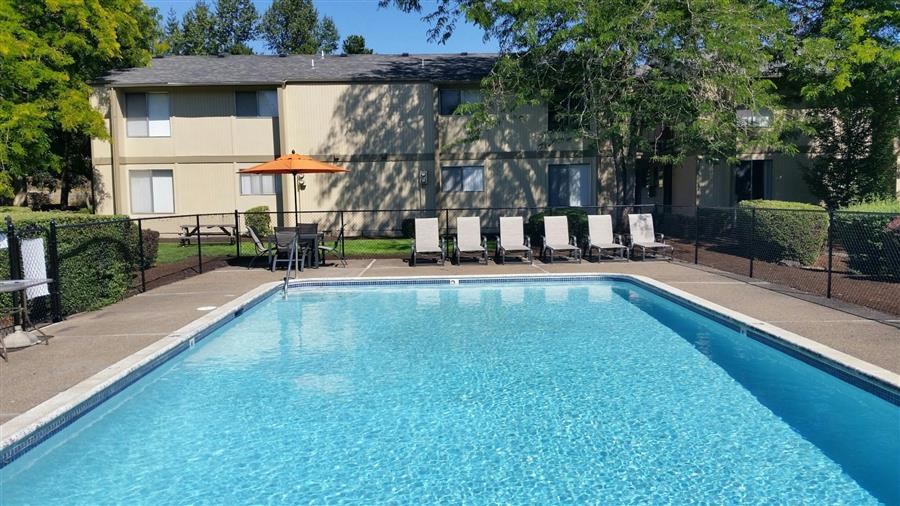 a swimming pool with chairs and a building in the background