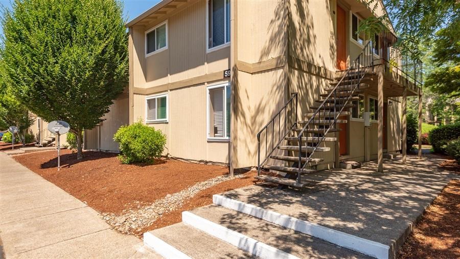 an apartment building with stairs and a sidewalk