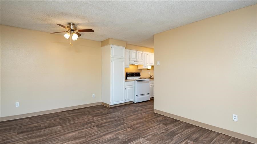 an empty living room and kitchen with a ceiling fan