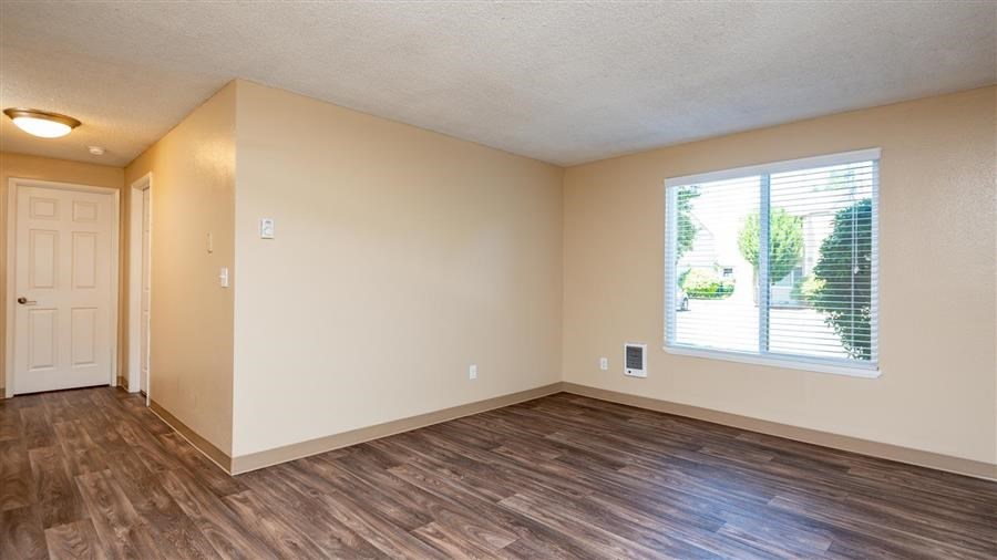 an empty living room with a large window and wooden floors