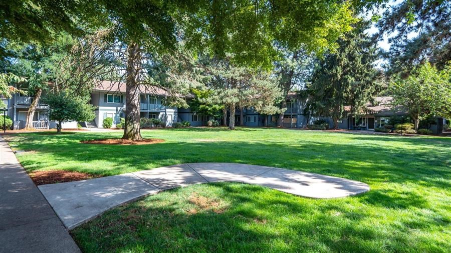 a park with grass and trees in front of a building