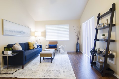 A living room with a blue couch, a coffee table, and a painting on the wall.