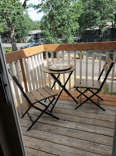 A table with two chairs on a wooden deck.