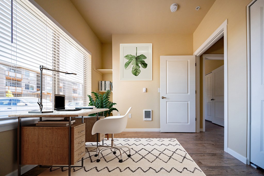 A room with a desk, chair, and a framed picture of a leaf on the wall.