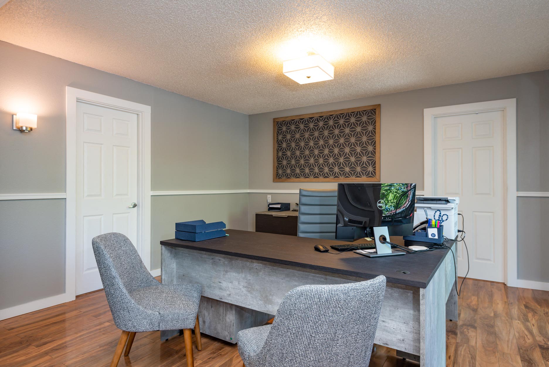 grey desk with two grey chairs in front.