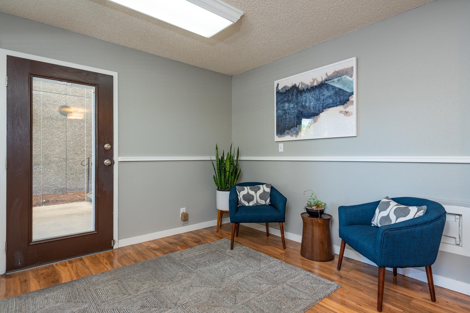 a living room with two blue chairs and a door to a porch