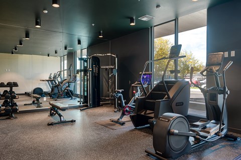 A gym with a variety of equipment including treadmills, weights, and exercise machines.