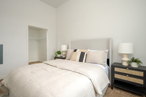 A bedroom with a large bed and two lamps on bedside tables.