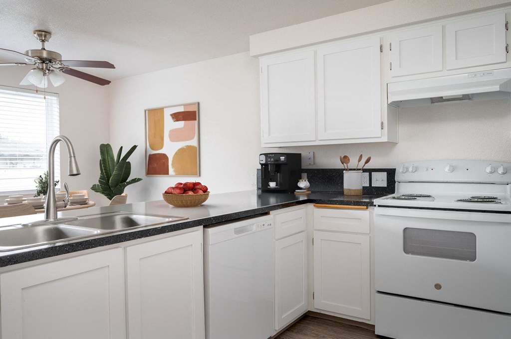 a kitchen with white cabinets and white appliances and a sink