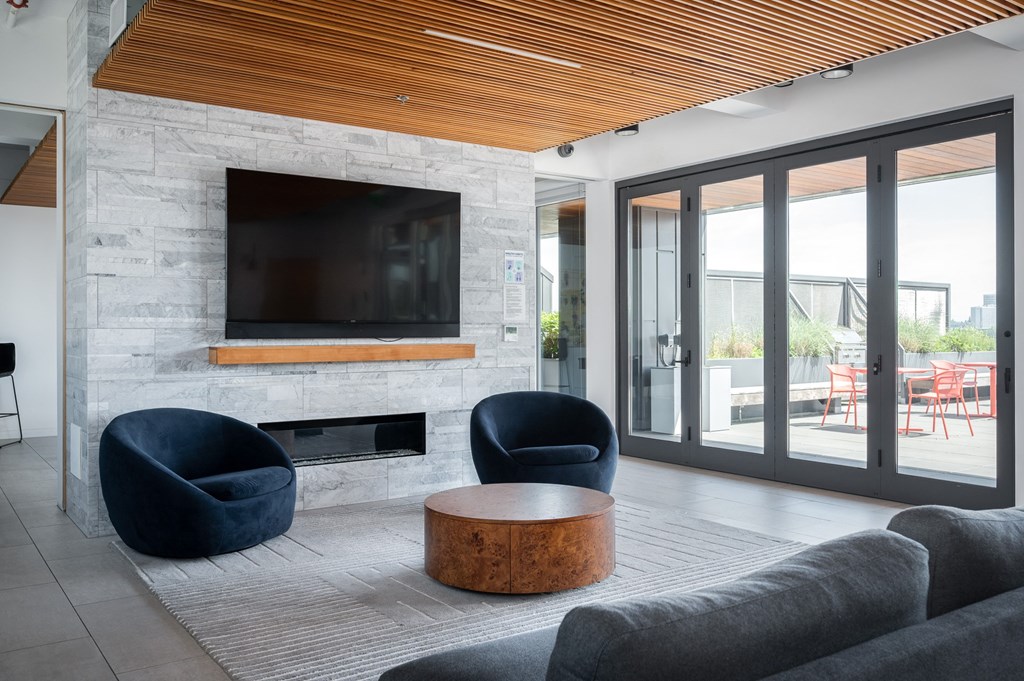 this living room has a large stone fireplace with a wooden mantle and a large flat screen tv