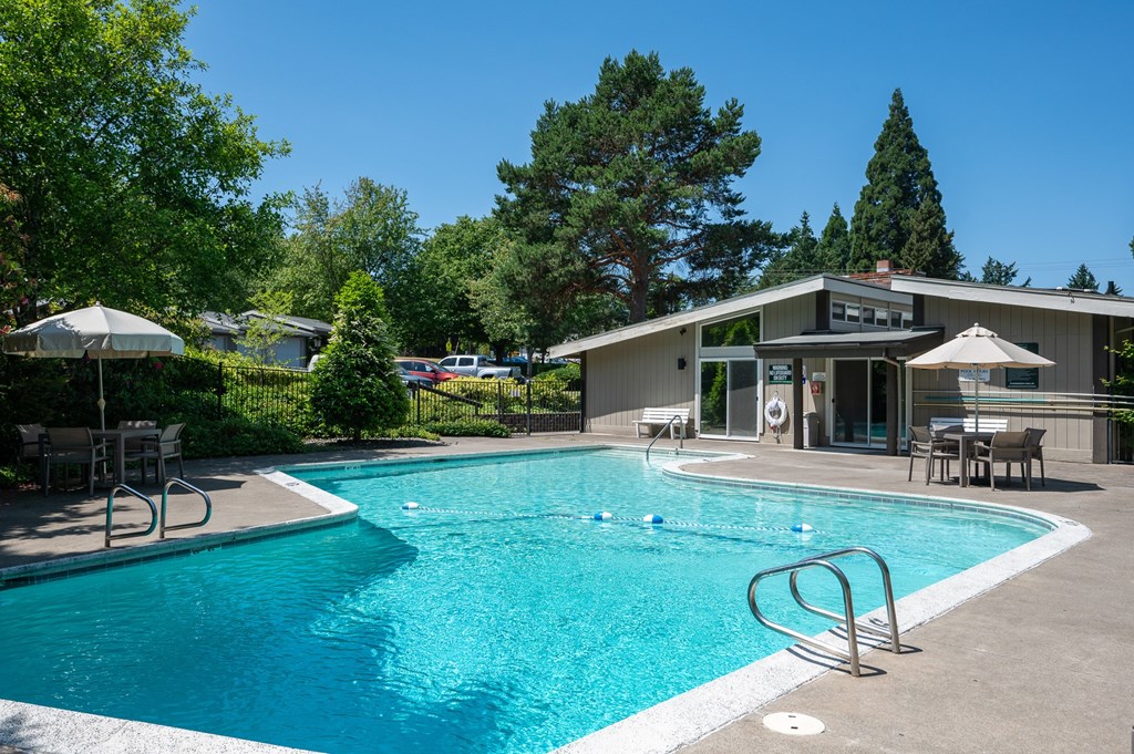 A swimming pool surrounded by trees and a building in the background.