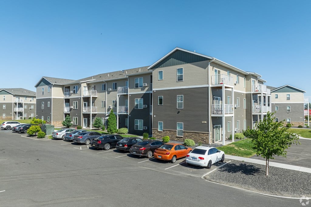 an apartment building with cars parked in a parking lot